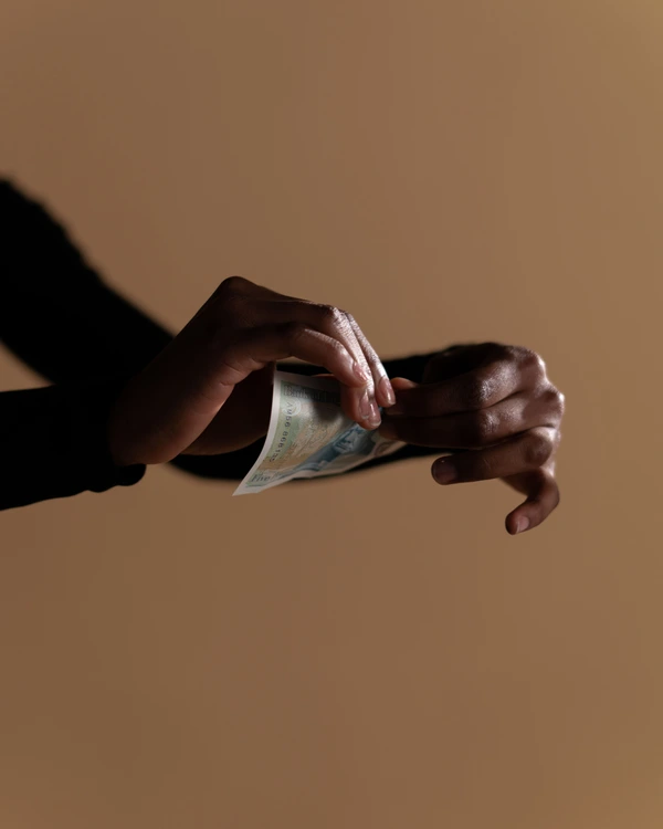 Des mains déchirent un billet.